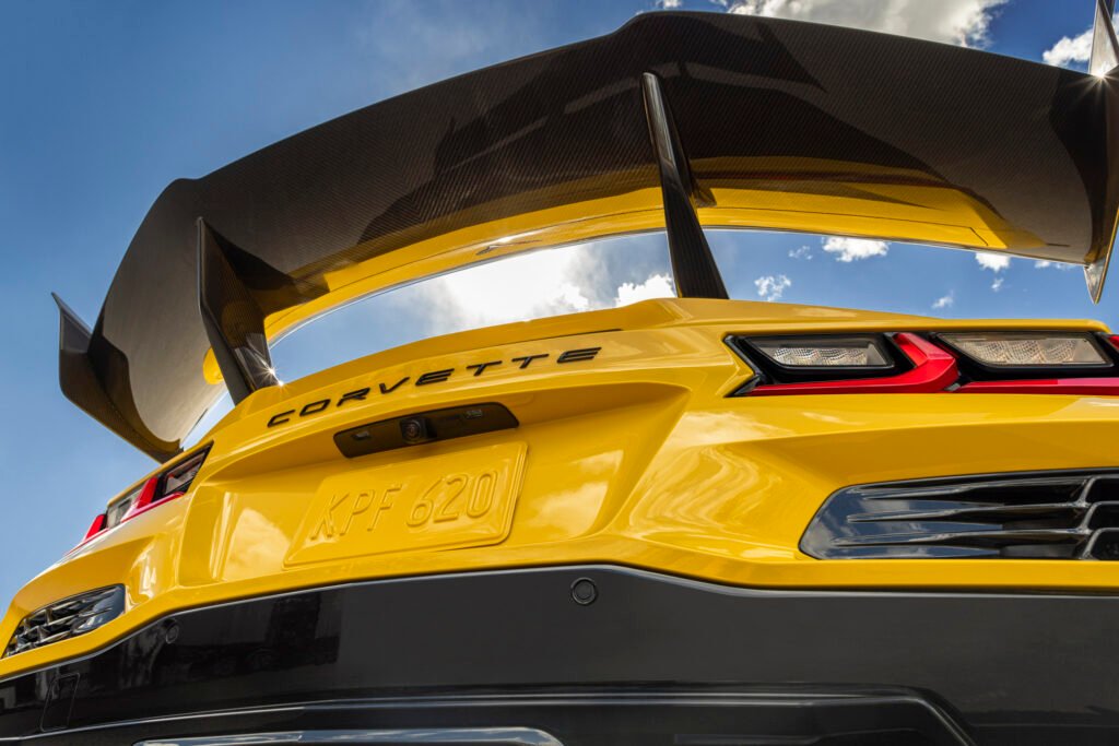 Yellow Chevrolet Corvette ZR1 coupe shot low from behind, looking up at its carbon fiber high wing and uprights